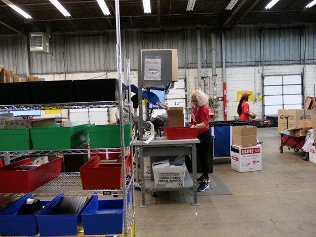 Woman in a warehouse scanning packages at her station