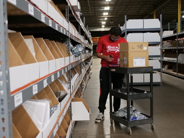 Man pushing a cart through a warehouse with boxes on it