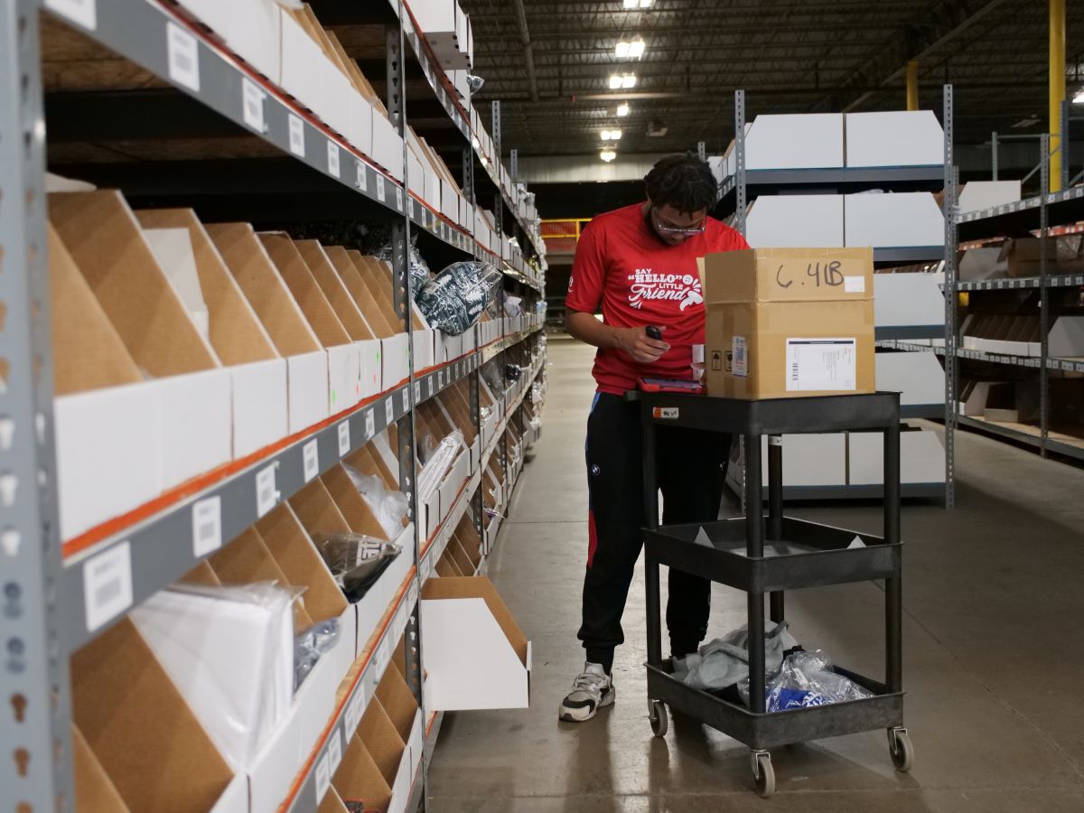 Man using a scanner to look for items to pick from the warehouse shelves for a special order.