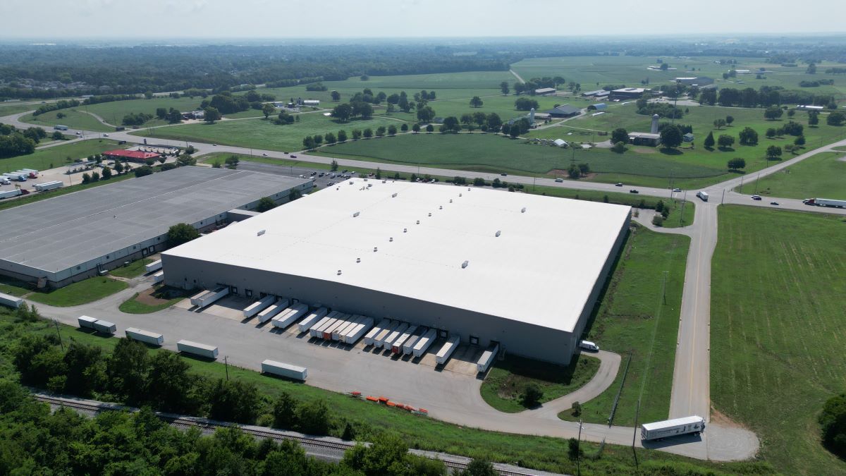 Sky view of a large warehouse. Many trucks are lined up in the back, loading product for the day. 