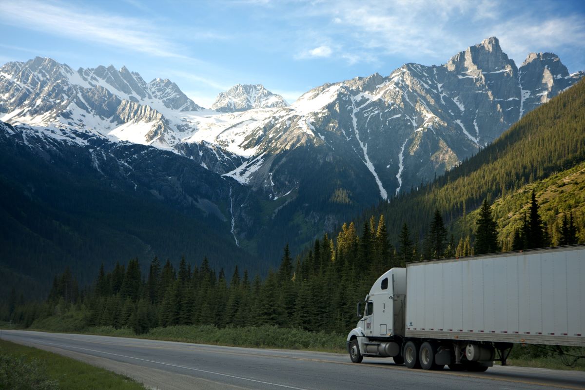 A big rig or 18-wheeler driving down a highway with mountain landscape in the background