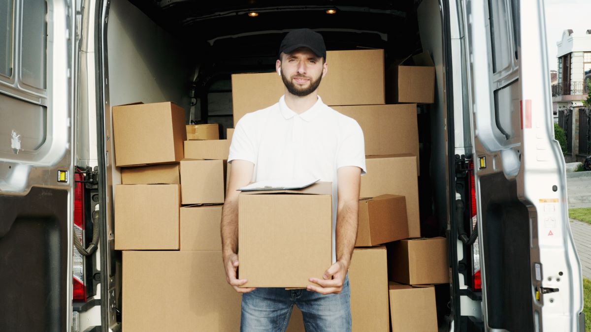 Man holding a box while standing in front of the back of a van filled with boxes