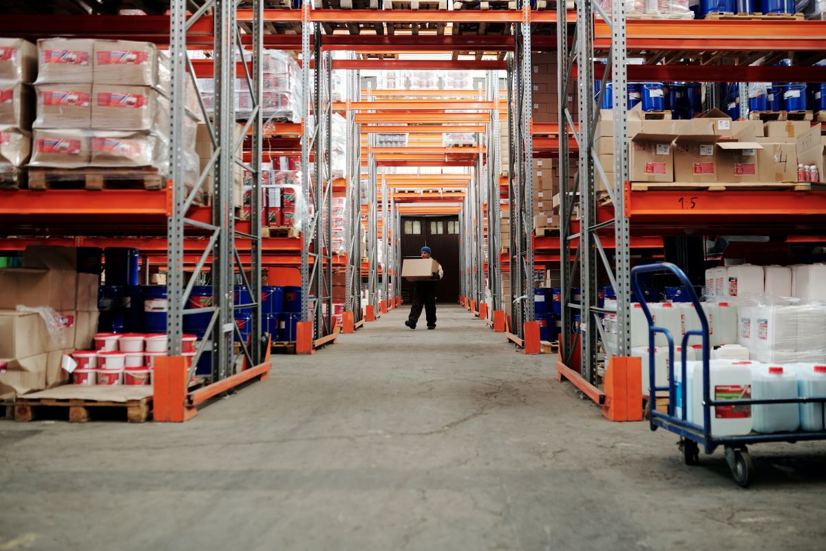 A man carrying a box at the end of a large warehouse